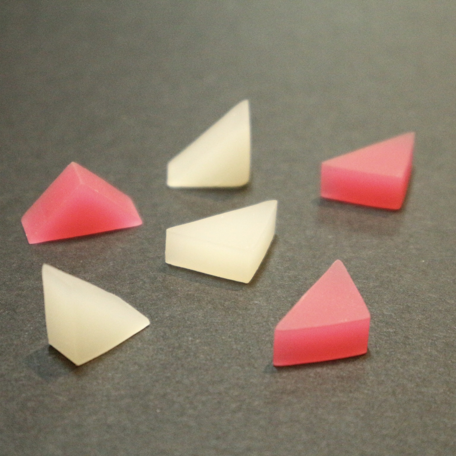 pink and white triangular prism shape erasers being scattered